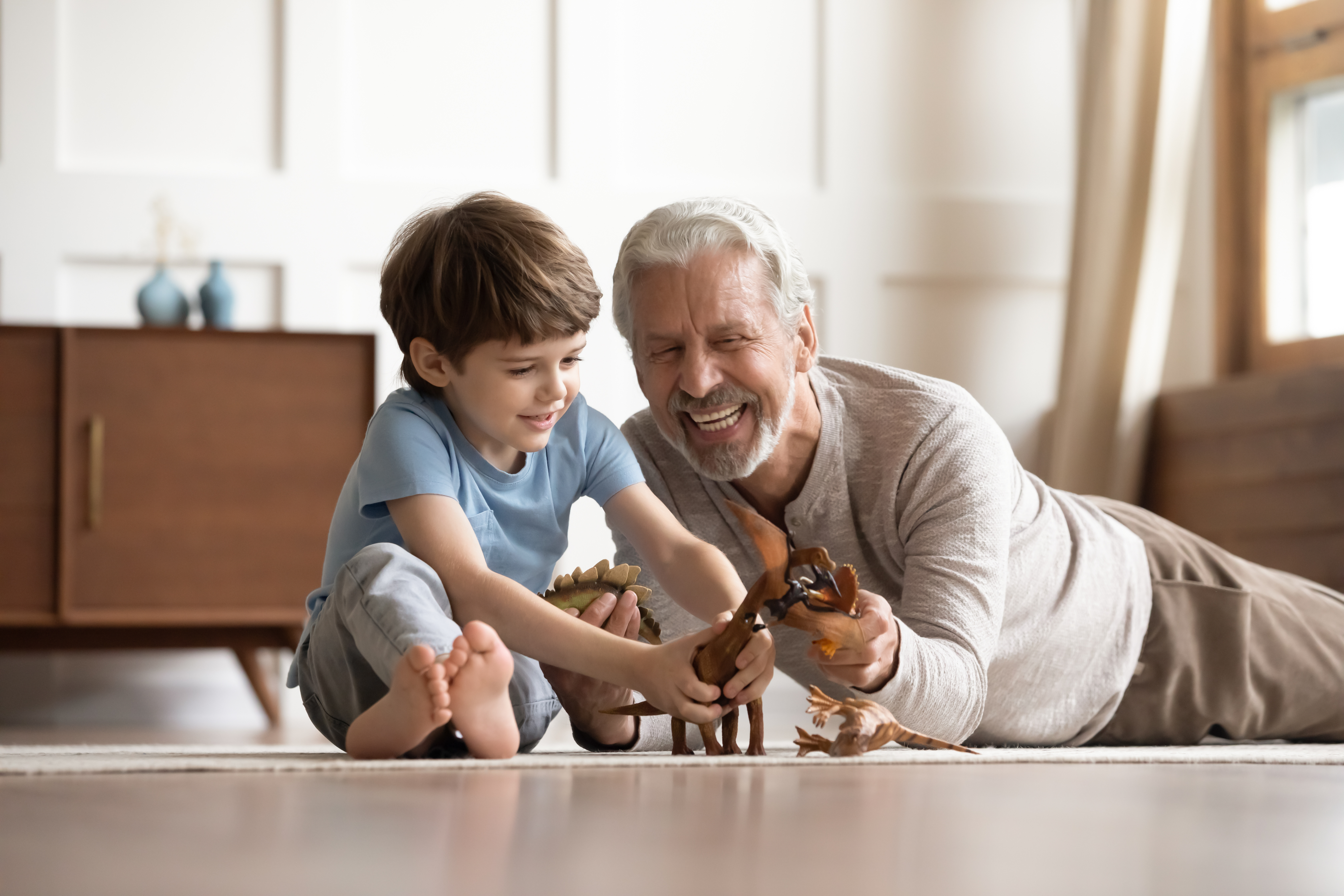 Happy mature grandfather play toys with little grandson